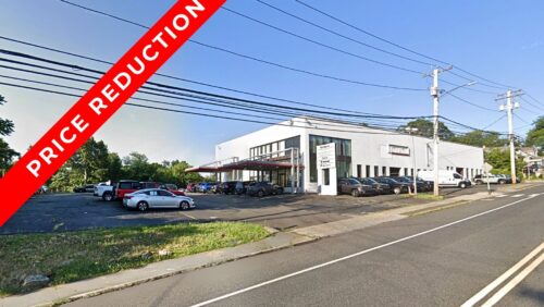 Industrial redevelopment opportunity at 387 Tunxis Hill Road, Fairfield, CT, featuring a large white commercial building with a $466,000 price reduction banner.