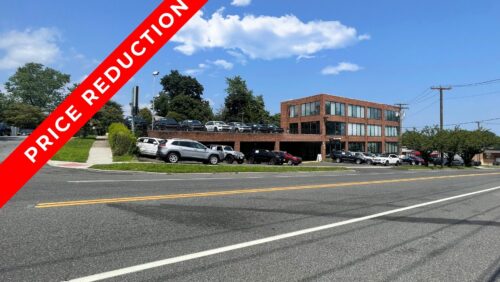 Large white commercial building at 360 Tunxis Hill Road, Fairfield, CT, featuring a prominent $500,000 price reduction banner and extensive parking.