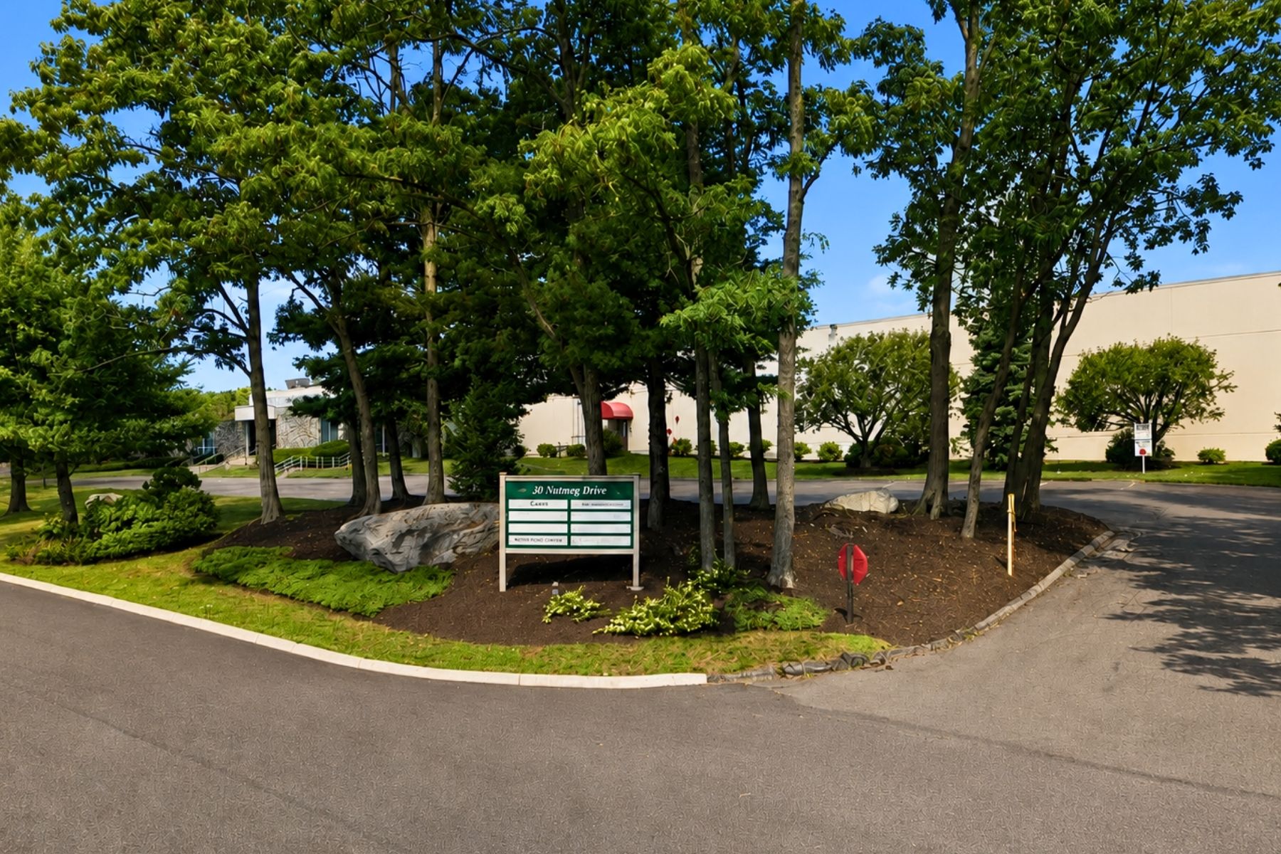 30 Nutmeg Drive Trumbull CT - Cul-de-Sac Entrance and Property Signage Landscaped cul-de-sac entrance with lush green trees and prominent monument property signage at 30 Nutmeg Drive in Trumbull, Connecticut.