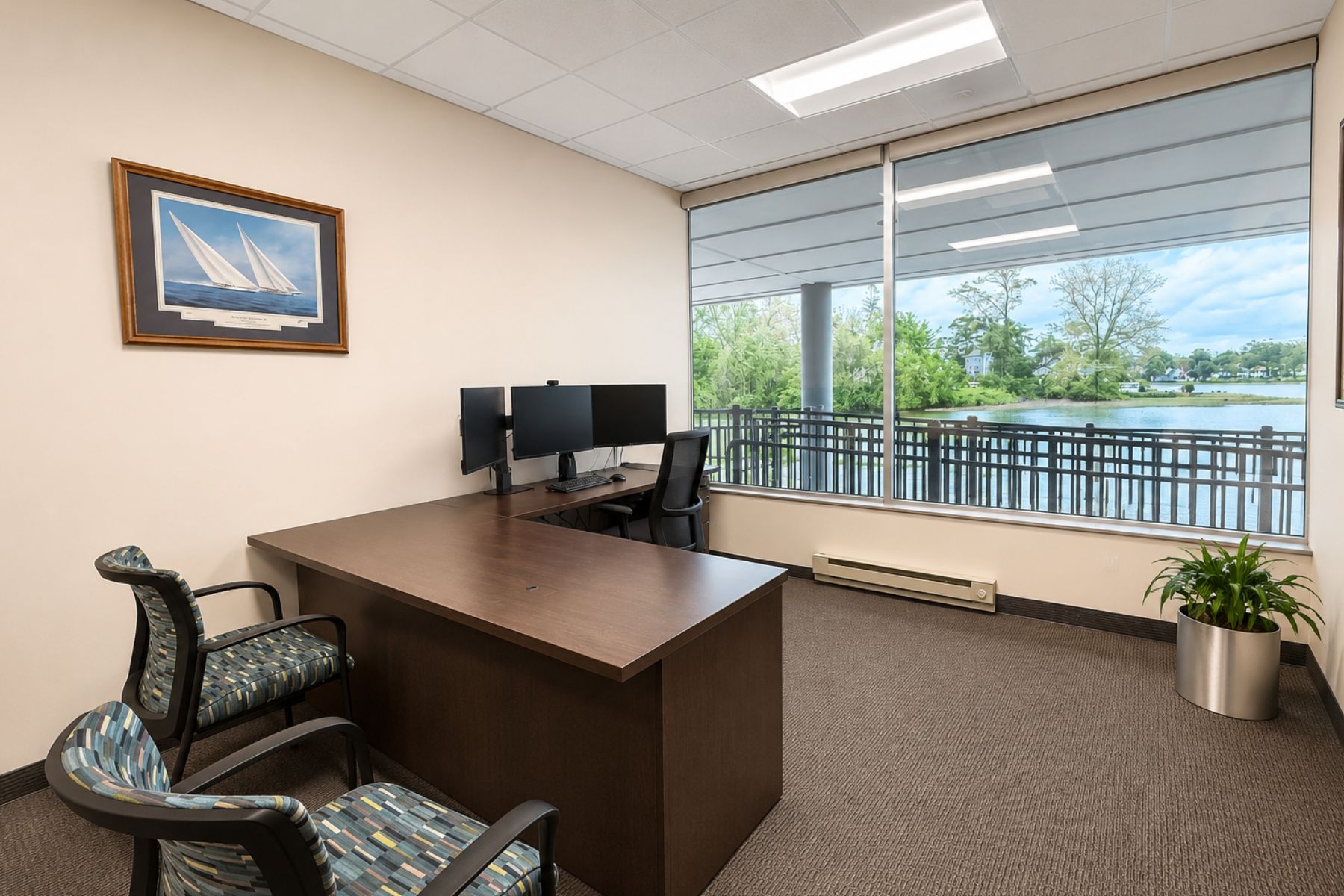 First Floor Suite - Private Office with Views of Ash Creek Bright private office at the One Post Road commercial office building in Fairfield, CT, featuring a dark wood desk, guest seating, and large windows with waterfront views of Ash Creek.