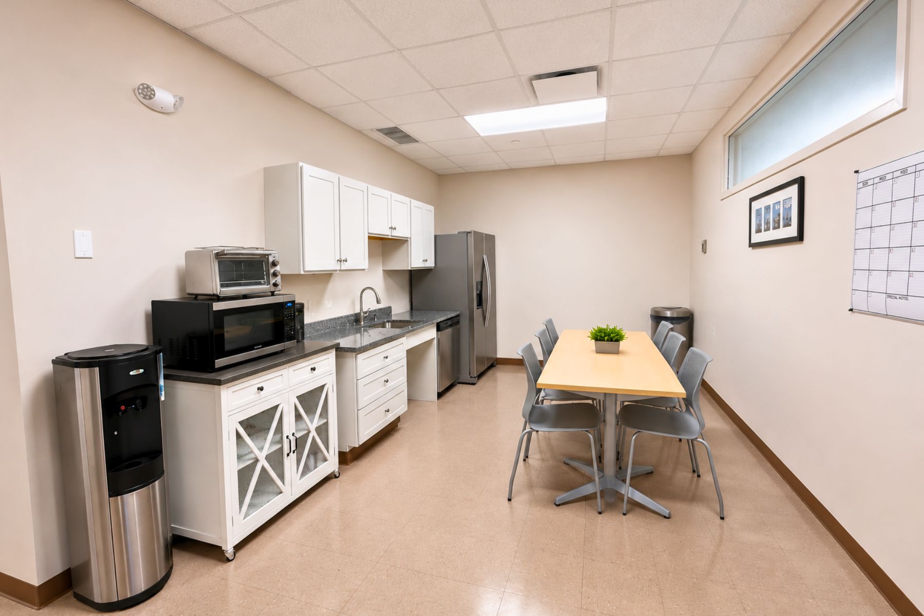 First Floor Suite - Well-Appointed Kitchenette With Seating Area and Appliances Well-appointed commercial office kitchenette featuring modern white cabinetry, appliances, and a dedicated dining seating area at One Post Road in Fairfield, CT.
