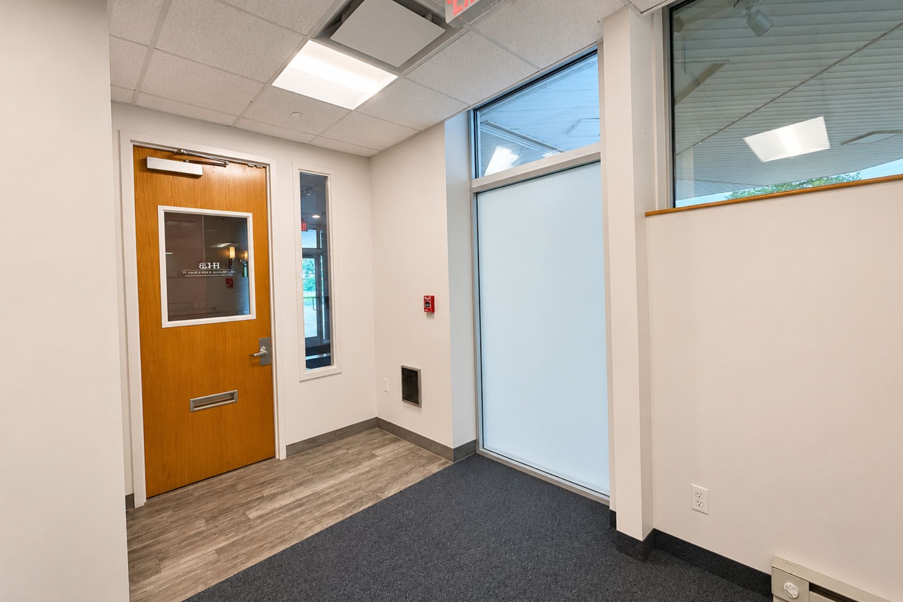 Secure Entrance to Suite with Waiting Area and Reception Secure entrance to the first-floor commercial office suite at One Post Road in Fairfield, CT, featuring a glass-paneled wooden door and a bright waiting area.