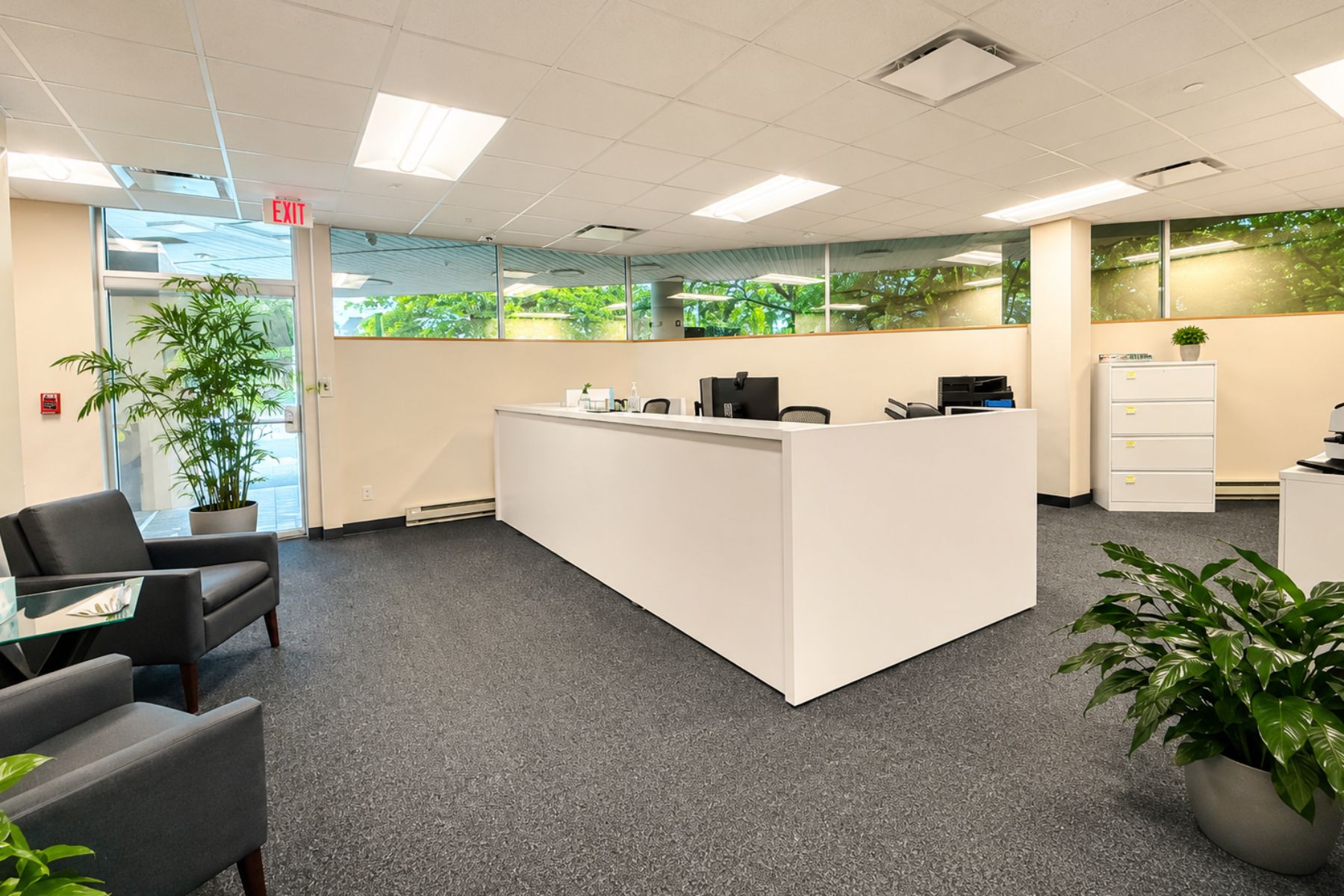 Professional Reception with Seating and Ample Natural Light Bright commercial office reception area at One Post Road in Fairfield, CT, featuring a modern white desk, guest seating, and ample natural light from large windows.
