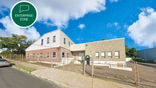 Exterior view of 9,506 SF industrial building at 229 & 261 Merriam Street, Bridgeport, CT, featuring a gated parking lot and loading dock.