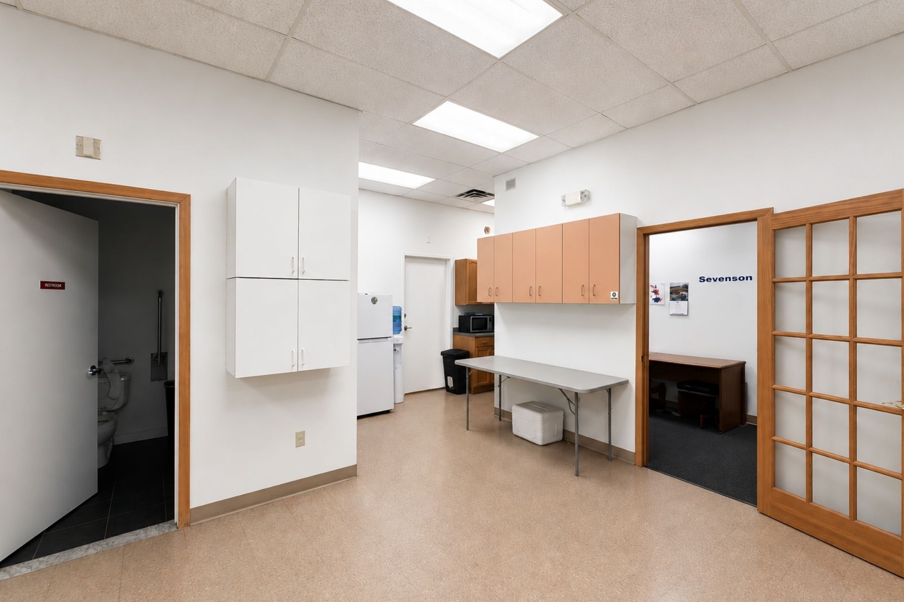 Dedicated Employee Break Area Featuring Full Plumbing Hookups and Modern Cabinetry for Kitchenette Use Modern employee break room with light wood upper cabinets, white lower cabinets, full plumbing hookups, and a spacious countertop.