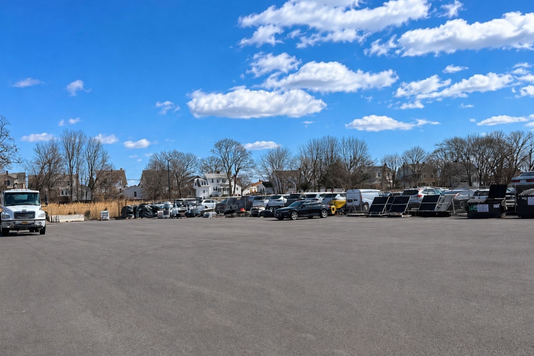 Gated Rear Lot Provides Additional Parking Large paved commercial parking lot behind a building, showing fenced boundaries and several parked vehicles.