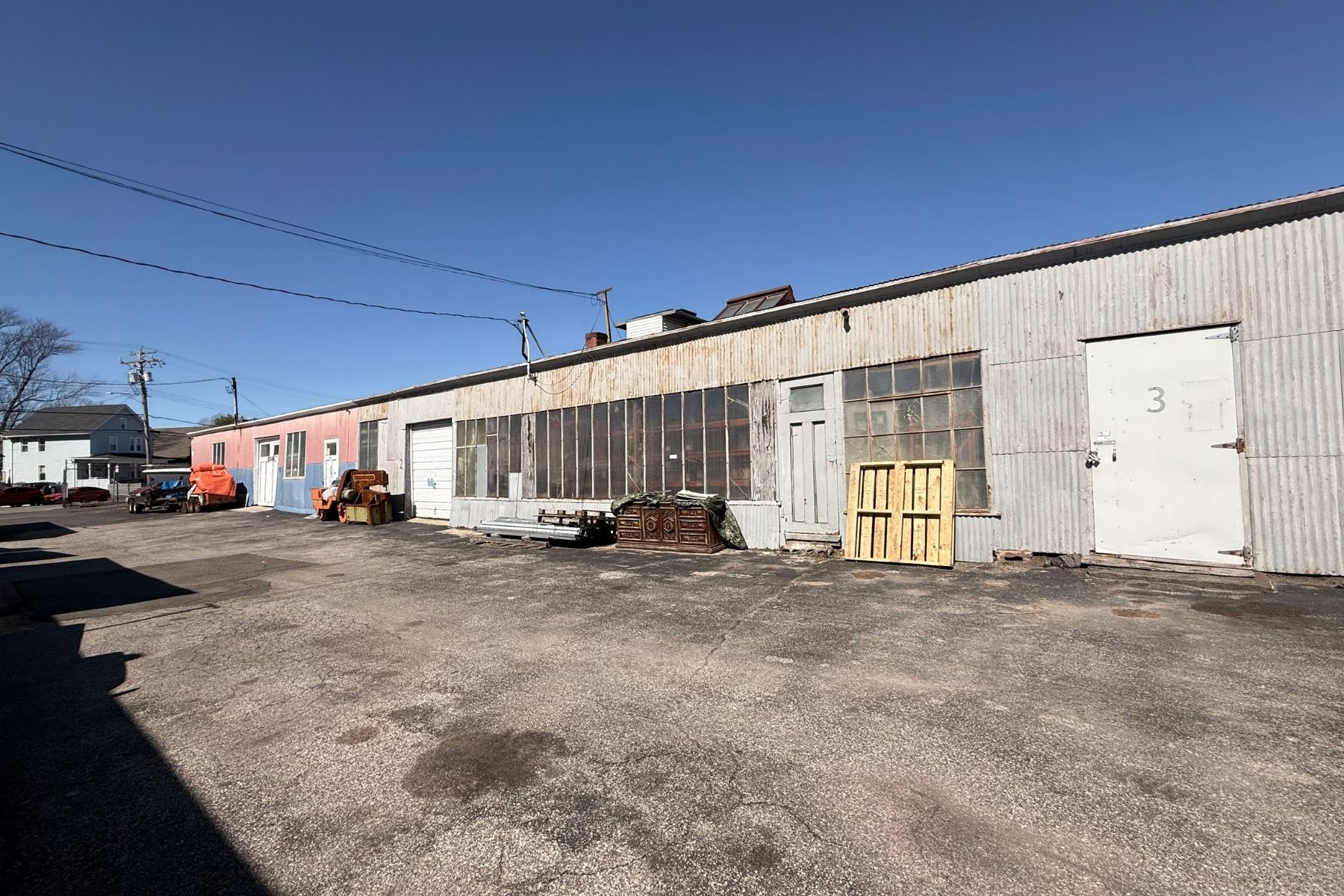 3,568 SF Warehouse Divided into Bays Each with a Drive-In Door Exterior view of the 7,427 SF industrial brick building at 100-120 Silliman Avenue, Bridgeport, CT, featuring a drive-in door and secure gated entry.